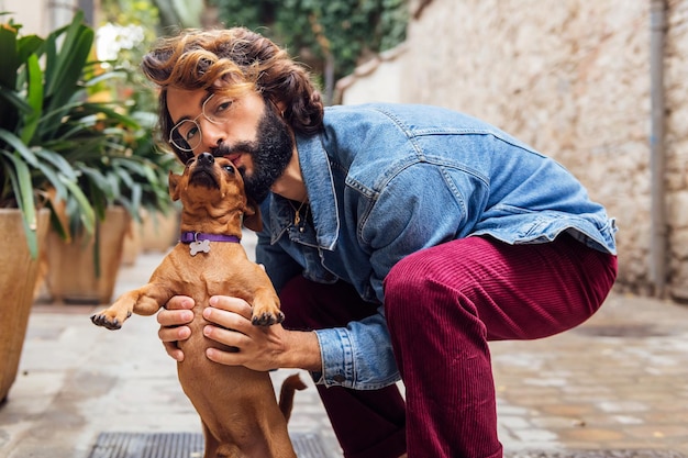 彼の小さな犬にキスをするひげを持つ若者