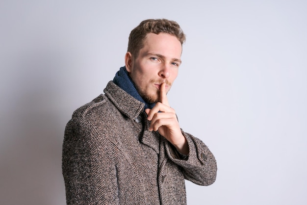 Young man with beard stands on light background with copy space for your