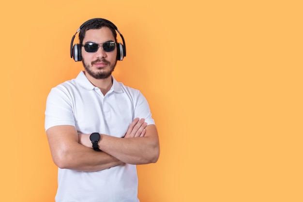 Young man with beard and sunglasses listening to music with wireless headphones Look at camera