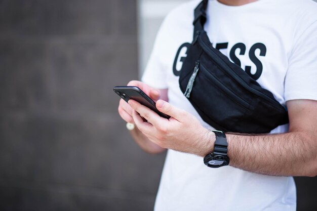 Young man with a beard walking and talking on a cell phone good\
talk happy young bearded man talking on the mobile phone and\
looking away while standing near the grey wall video chat\
phone