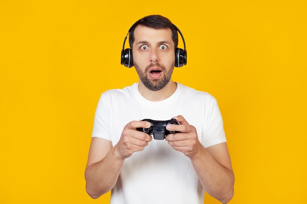 ビデオゲームをしている白いTシャツのひげを持つ若い男