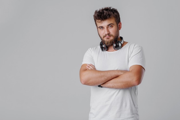 Un giovane con la barba con le cuffie senza fili intorno al collo