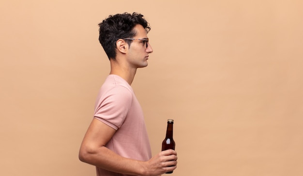 Young man with a beer on profile view looking to copy space ahead, thinking, imagining or daydreaming