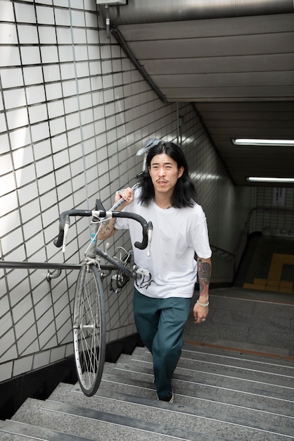 屋外で自転車を持っている若い男