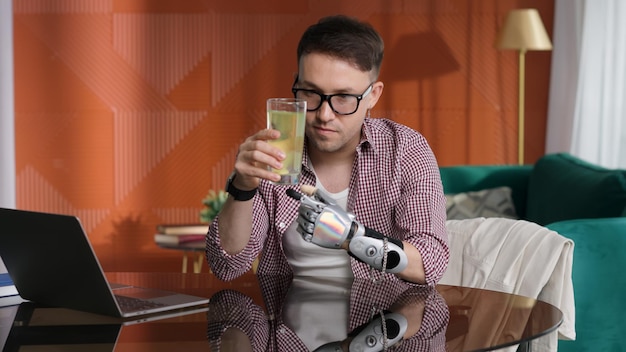 Young man with bionic arm sit down and put medicine in glass of water at home