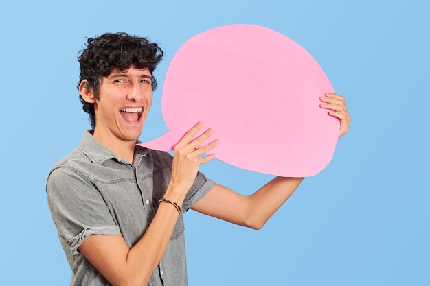 Young man with blank dialogue bubble on blue flat lay