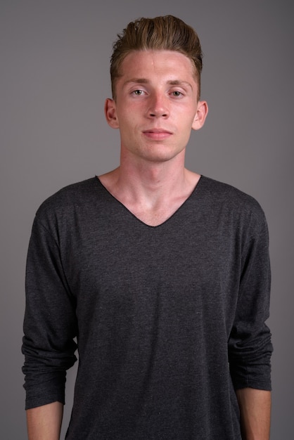 Young man with blond hair against gray background