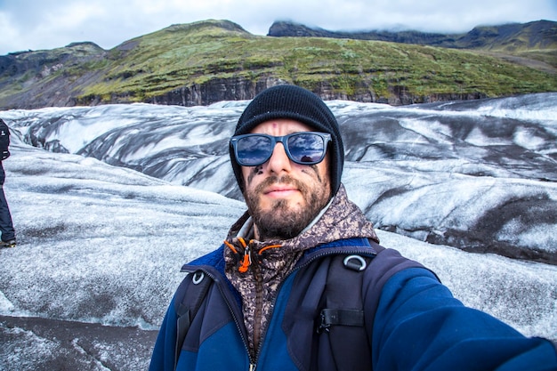 Un giovane con stivaletti e martello durante il trekking del ghiacciaio svinafellsjokull in islanda