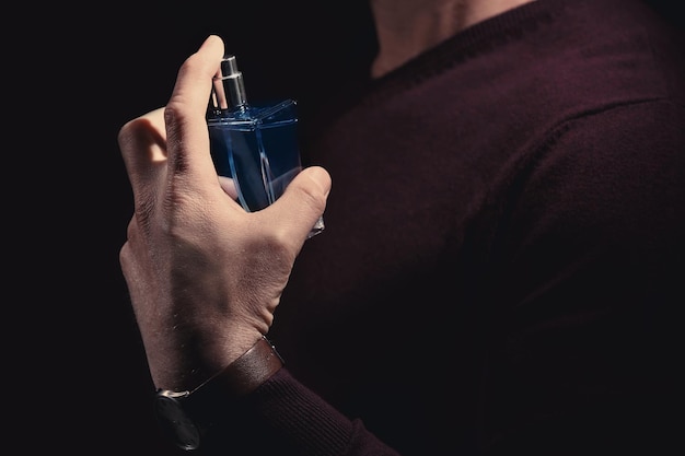 Young man with bottle of perfume closeup