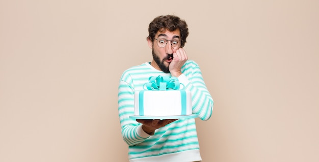 Young man with a cake against flat wall