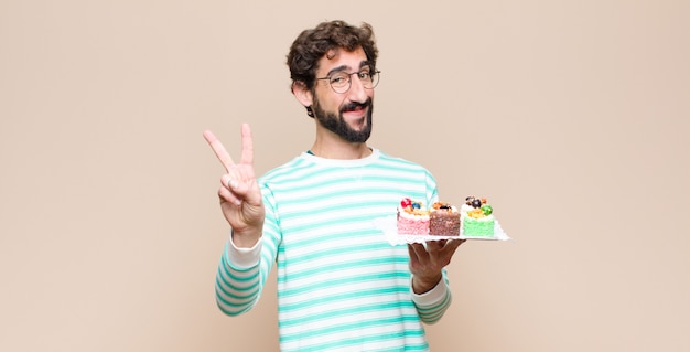 Young man with a cake against flat wall