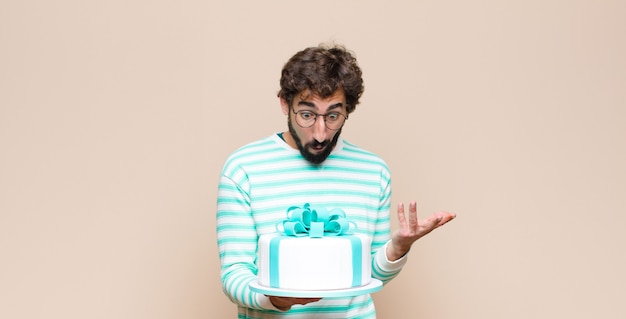 Photo young man with a cake against flat wall