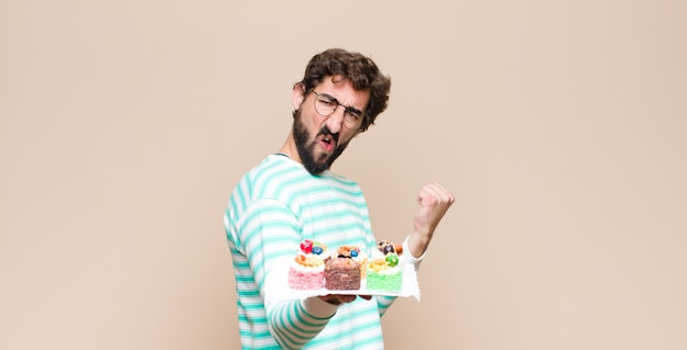 Young man with a cake against flat wall