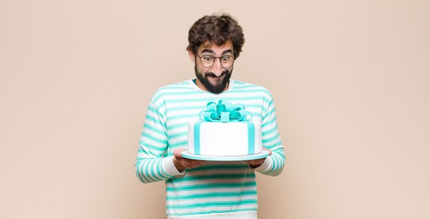 Young man with a cake against flat wall