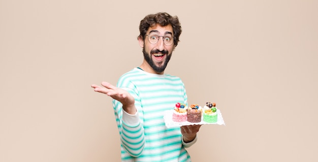 Young man with a cake against flat wall