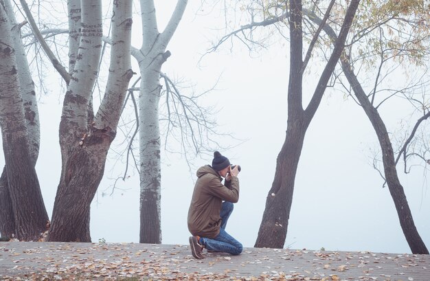 A young man with a camera photographs the autumn nature. 