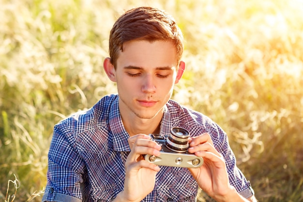 Un giovane uomo con una fotocamera scattare foto dei raggi del sole sfondo naturale colorato