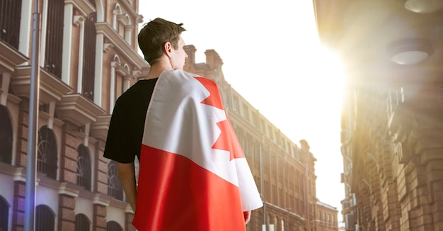 A young man with a canada national flag on the soulders patriotism and proud feelings