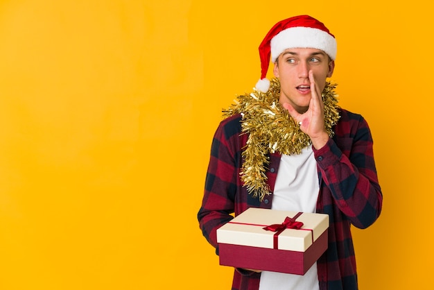 Young man with christmas hat holding a present