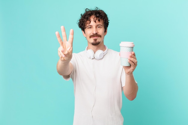 Young man with a coffee smiling and looking friendly, showing number three