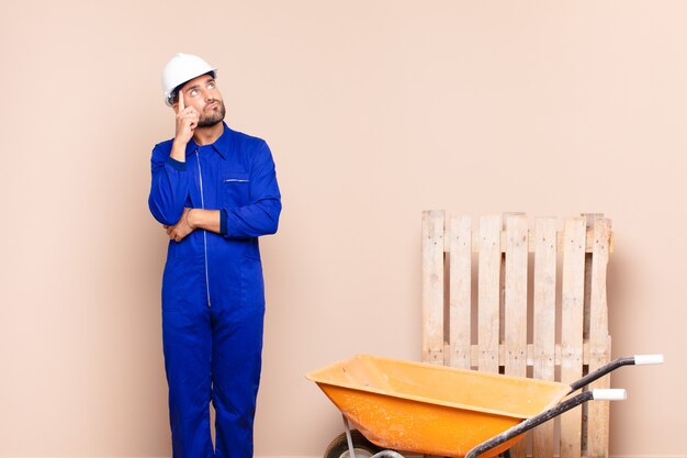 Young man with a concentrated look, wondering with a doubtful expression, looking up and to the side construction concept