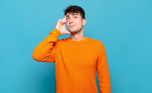 Young man with a concentrated look, wondering with a doubtful expression, looking up and to the side