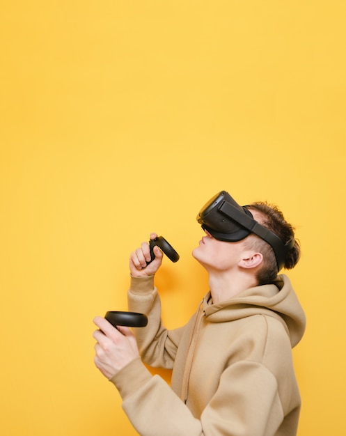 Young man with controller in his hands and VR helmet playing video games