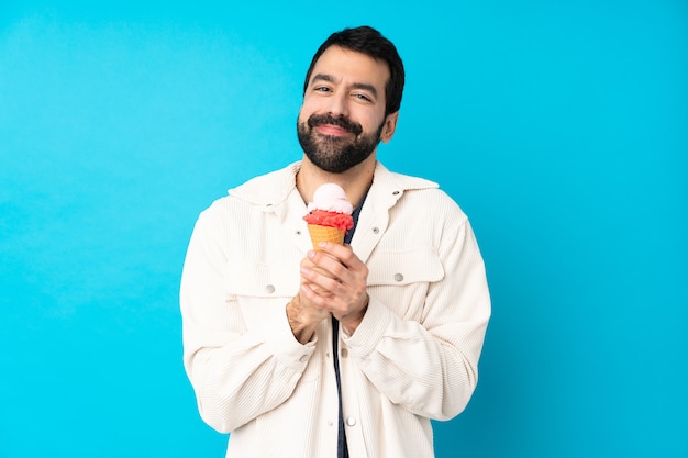 고립 된 파란색 벽 위에 코 넷 아이스크림 젊은 남자