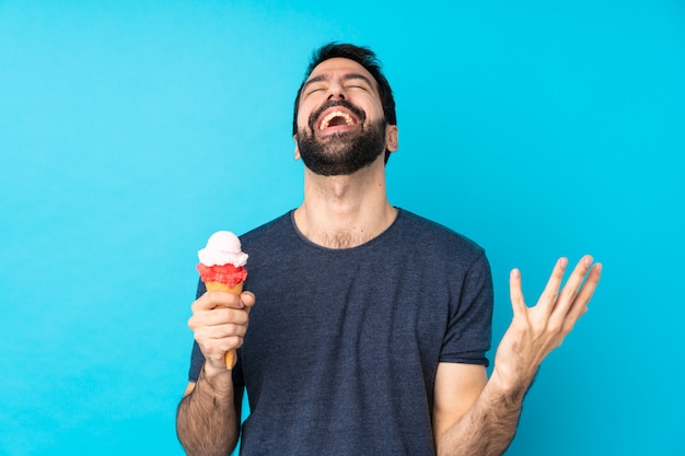 Young man with a cornet ice cream over isolated blue