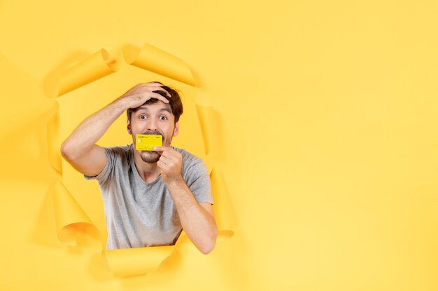 young man with credit card on the yellow background shopping money sale bank