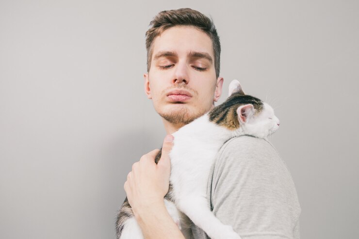 明るい背景にかわいい面白い猫と若い男