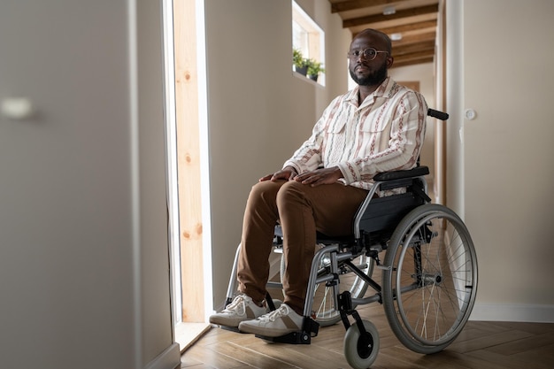 車椅子に座ってカメラを見ている障害を持つ若い男