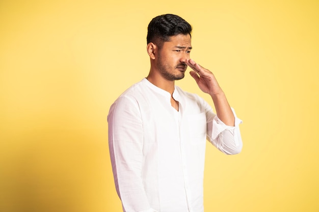 Young man with disappointed waving hand in front of nose