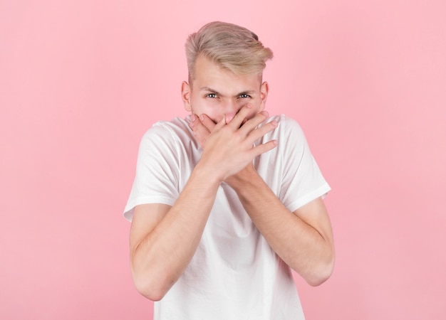 Young man with disgust on his face on pink. negative emotion\
facial expression.