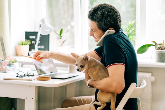 The young man with dog working from home