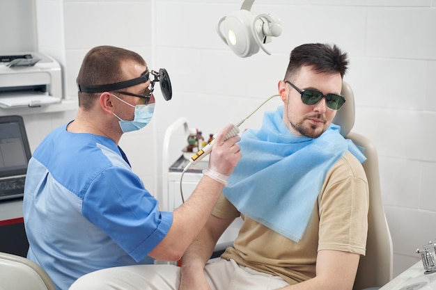 Young man with earache visiting otorhinolaryngologist office