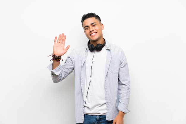 Young man with earphones saluting with hand with happy expression