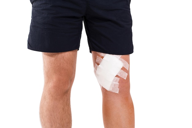 Young man with elastic bandage on knee isolated on white