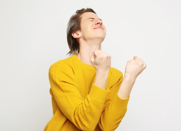 Young man with emotions on his face a grey background