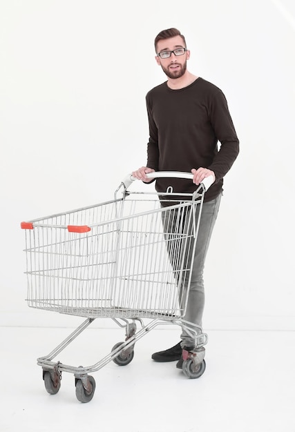 Young man with empty shopping cart isolated on white