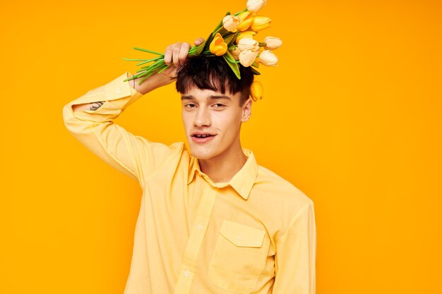 A young man with a fashionable hairstyle in yellow shirts with flowers yellow background unaltered