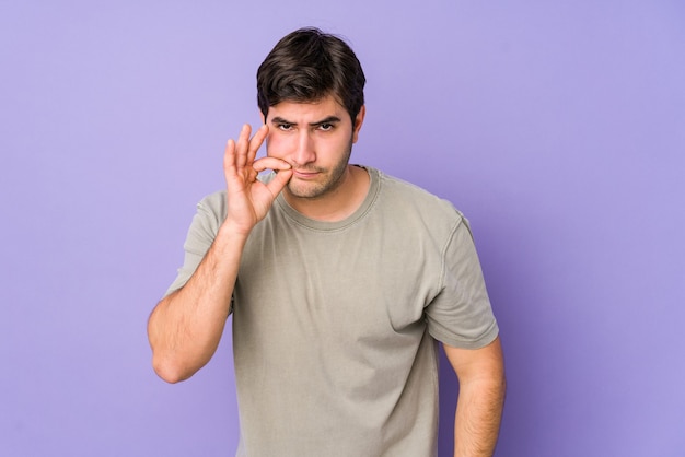 Young man with fingers on lips keeping a secret.