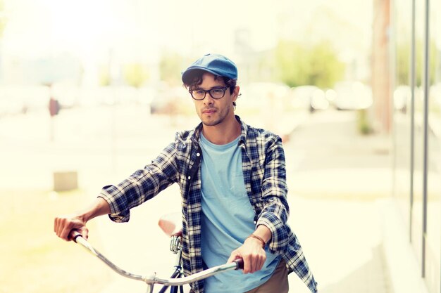 固定ギアの自転車で街を歩く若い男