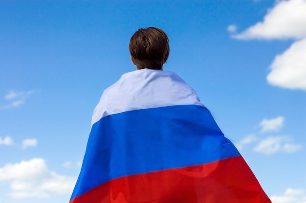 Young man with the flag of Russia standing with his back