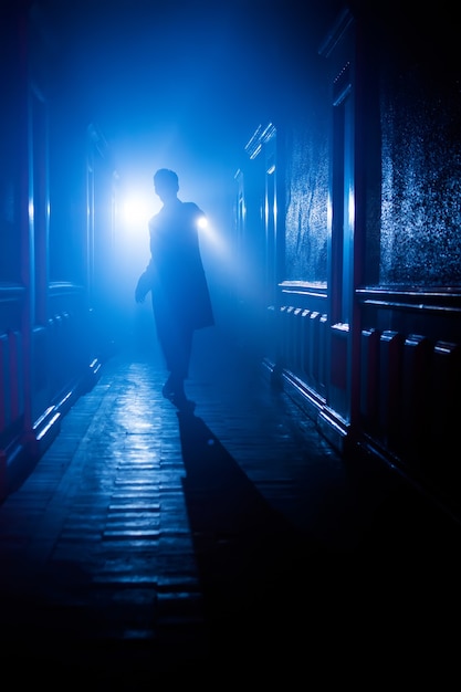 Молодой человек с фонариком в коридоре. За кадром съемок.