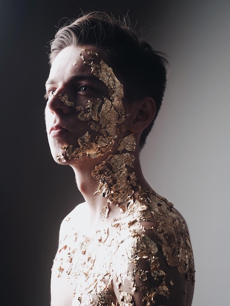 young man with foil on skin against wall
