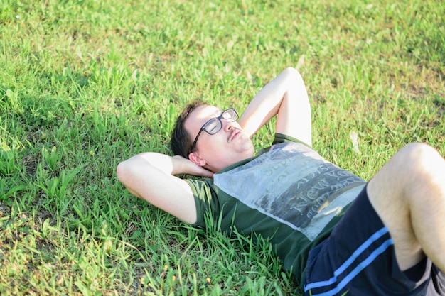 Young man with glasses and green tshirt doing situps and exercising in park