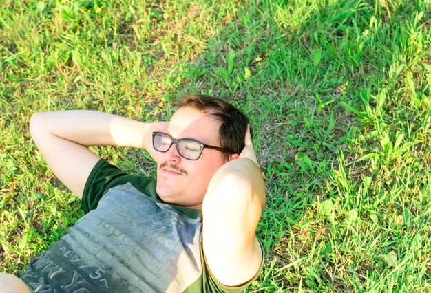 Young man with glasses and green tshirt doing situps and exercising in park