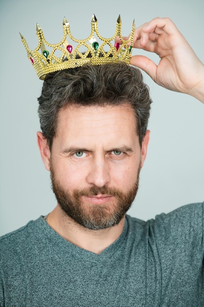 Young man with golden crown of king over gray background handsome man wearing king crown