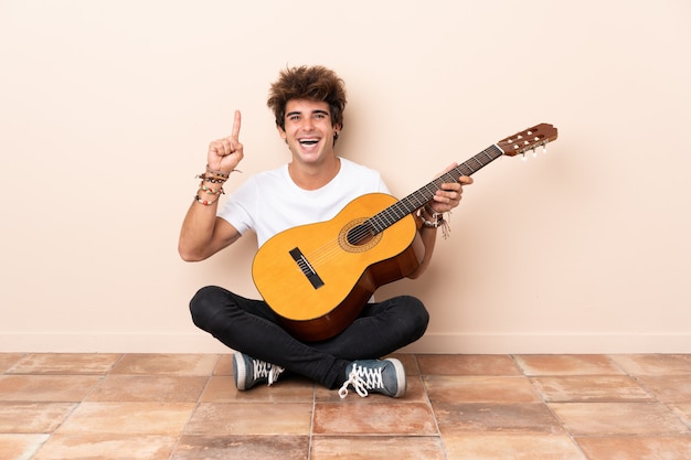 Young man with guitar sitting on the floor